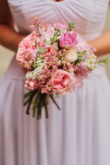 Bride holding a wedding fine-art bouquet in pastel pink colors. closeup.