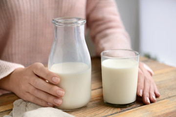 Woman drinking fresh milk at wooden table, closeup