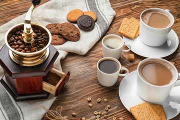 Cups with tasty aromatic coffee and cookies on wooden table