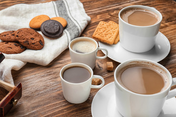 Cups with tasty aromatic coffee and cookies on wooden table