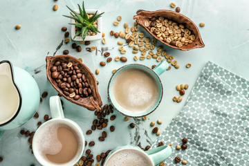 Cups of tasty aromatic coffee with jug of milk and beans on light table