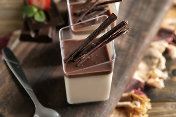 Glasses with tasty chocolate panna cotta on wooden board, closeup