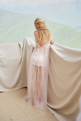 silhouette of young beautiful girl bride in a peignoir stands of the balcony overlooking the mountains