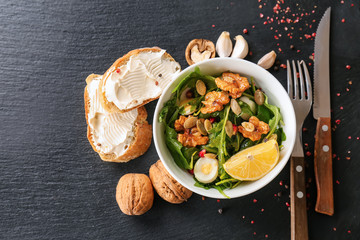 Delicious fresh salad with walnuts in bowl on dark table