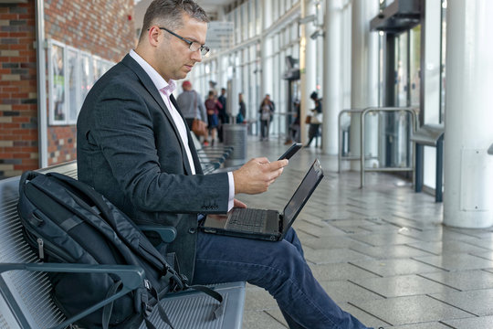 BUSINESS MAN USING HIS TABLET AND PHONE OUTSIDE OFFICE. Close-up of male hands using digital tablet outside, young hipster man working or typing on touch screen of tablet pc near modern office,