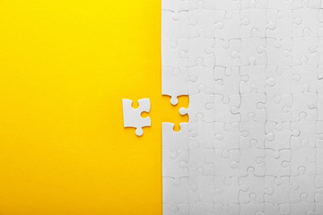 White jigsaw puzzle with piece on color background