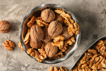 Bowl with tasty walnuts on grey table