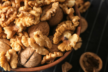 Bowl with tasty walnuts on table, closeup