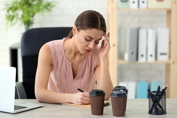 Woman suffering from headache while working in office