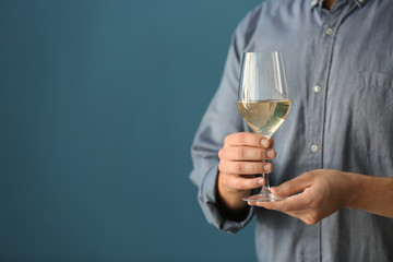 Man with glass of wine on color background, closeup