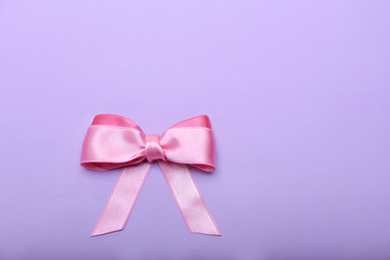 Beautiful bow made of pink ribbon on color background