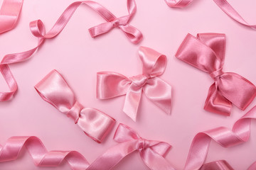 Pink ribbons and bows on color background