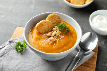 Bowl with tasty pumpkin cream soup on grey table