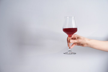 Female hand with glass of red wine on white background