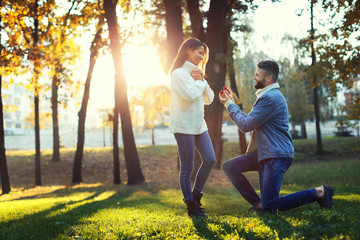 Young man proposing to his beloved in autumn park
