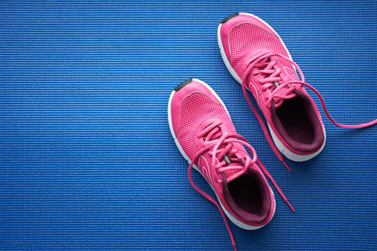 Pair of pink running sneakers for woman on a blue background. Top view