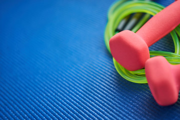 Set of jump rope and dumbeells on the blue background