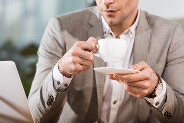 cropped shot of businessman drinking coffee at workplace