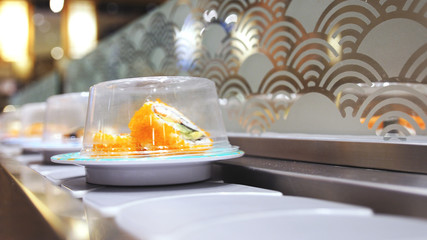 Close up of Sushi and rolls on plates moving around a sushi bar