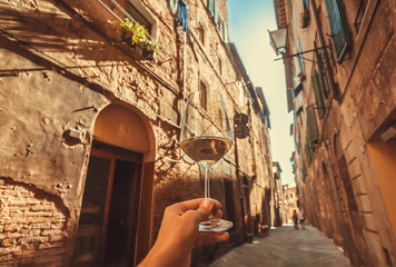Brick wall streets with wine glass in hand of tourist, ancient town of Tuscany. Historic Centre of...