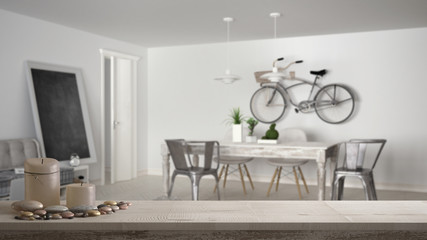 Wooden vintage table top or shelf with candles and pebbles, zen mood, over blurred living room with sofa and vintage dining table, minimal architecture interior design