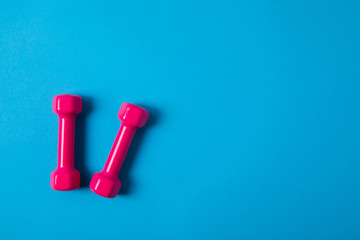 flat lay with pink dumbbells isolated on blue, minimalistic concept