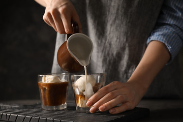 Woman pouring milk into glass with coffee and ice cream