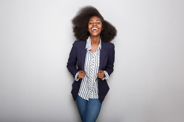 happy young black woman with blazer against gray background