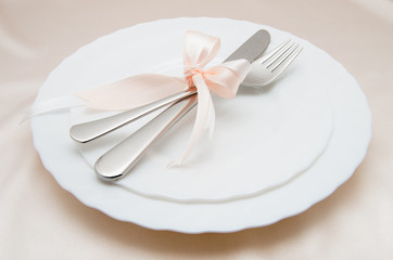 White plate, fork and knife on light background.