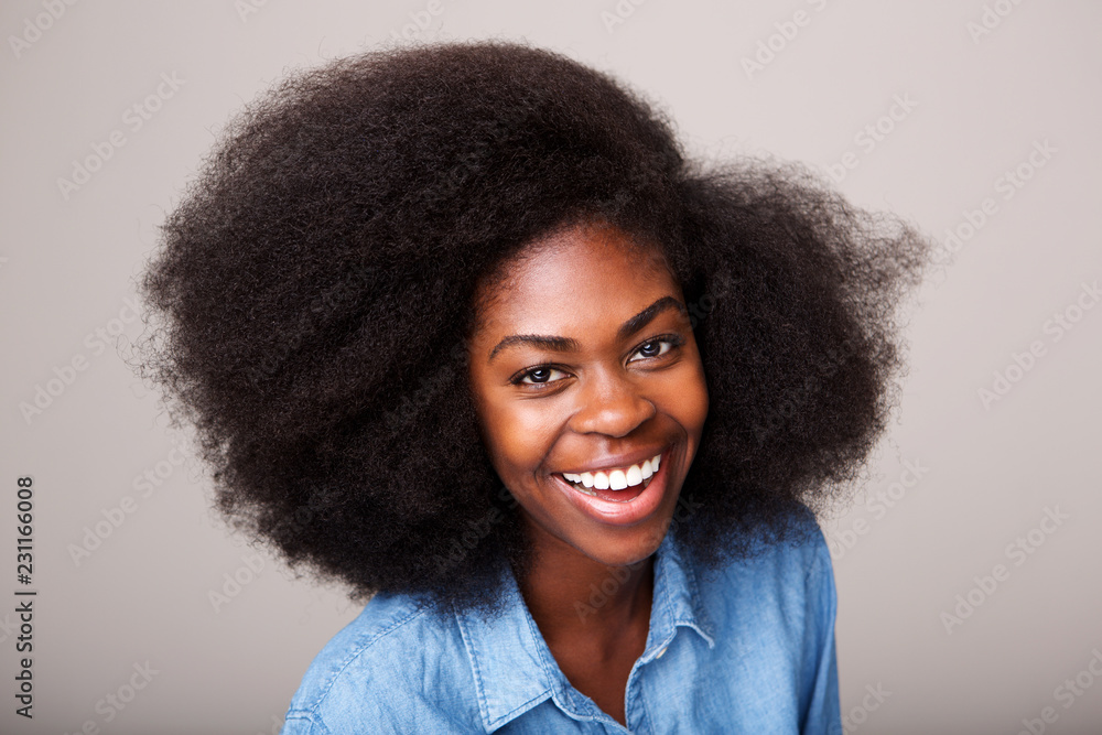 Wall mural Close up happy young african american woman laughing against isolated gray background