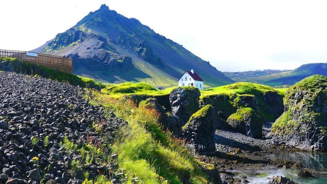 Natural landscape of Coastline with the basalt rocks formation and a lonely house at Arnarstapi Village in Iceland