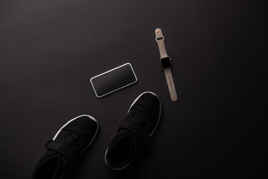 View From Above Of Smartphone, Smartwatch And Sneakers Isolated On Black