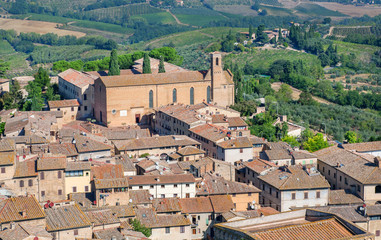 Fototapeta na wymiar Rooftop view on Tuscany town and fields. San Gimignano medieval city houses and natural landscape, Italy