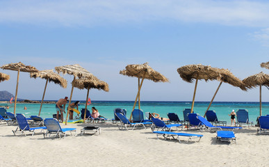 Greek beach on the Islands-Turquoise sea, blue sky, white sand - Umbrellas and blue sun loungers