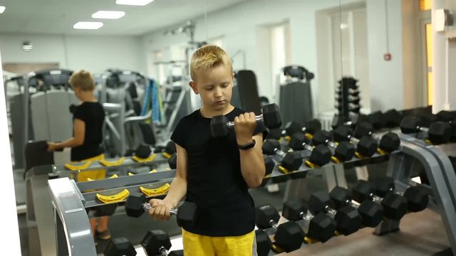 The boy does heavy dumbbell exercises for the biceps.