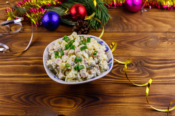 Traditional Russian festive salad Olivier and New Years decorations on wooden table