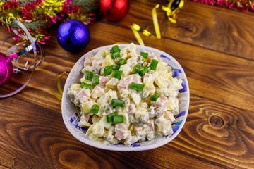 Traditional Russian festive salad Olivier and New Years decorations on wooden table