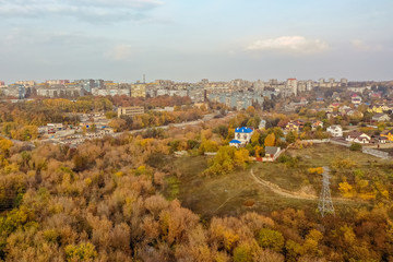 Aerial top view of colorful autumn forest in front of the city. Background of trees in yellow and green color.