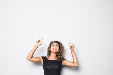 Portrait of happy curly woman pointing up and smiling against white background