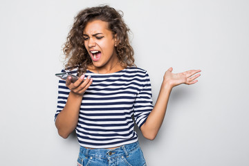 Portrait of american mixed race woman with afro hairstyle wearing t-shirt shouting into mobile phone being annoyed and angry isolated over white background