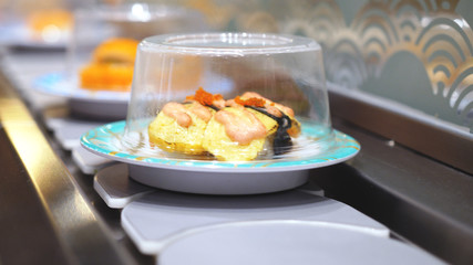 Close up of Sushi on plates moving around a sushi bar