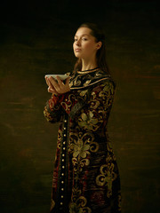 Girl standing in Russian traditional costume. Woman is wearing in old retro boyary outfit at darl studio