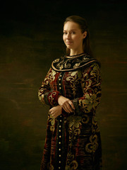 Girl standing in Russian traditional costume. Woman is wearing in old retro boyary outfit at darl studio