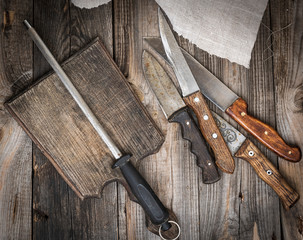  old brown wooden cutting board and knife with sharpening on the table