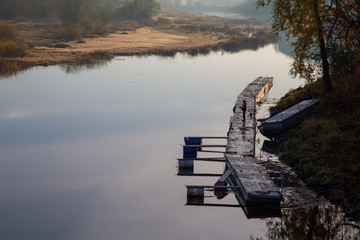 mężczyzna łowi ryby z pomostu nad rzeką o wschodzie słońca © Arkadiusz