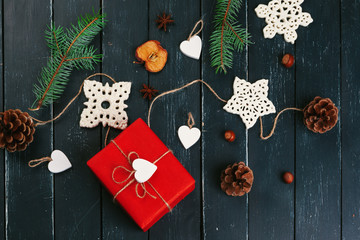 Christmas composition. Christmas gift, knitted blanket, pine cones, fir branches on wooden background.