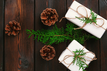 Christmas composition. Christmas gift, knitted blanket, pine cones, fir branches on wooden background.