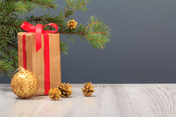 Fototapeta na wymiar Gift box, toy ball and fir tree branch on gray background