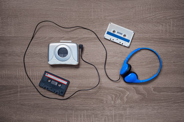 Vintage walkman, cassete and headphones on the wooden background