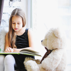 girl reading fairy tales on the window, near the Christmas tree,